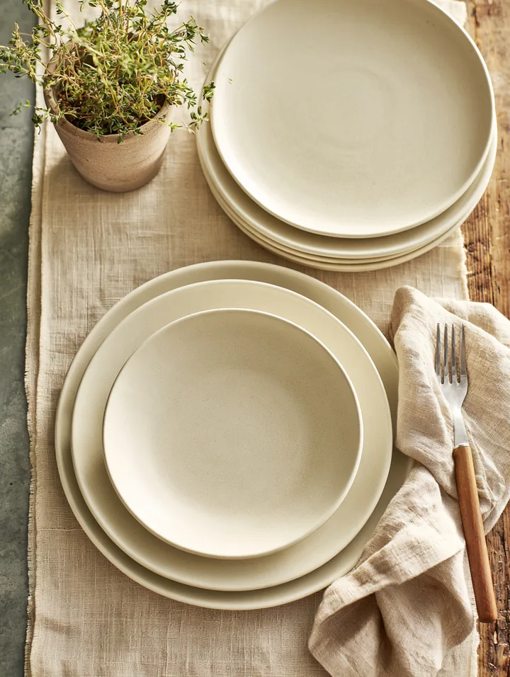 A new set of matte ceramic dinnerware stacked on a linen runner with a small potted herb — one way a $2,500 loan gets used